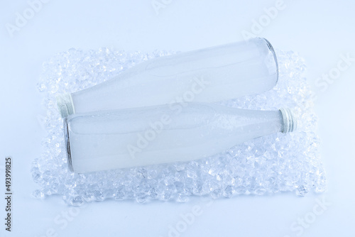 A white bottle with a soda drink on ice isolated.
