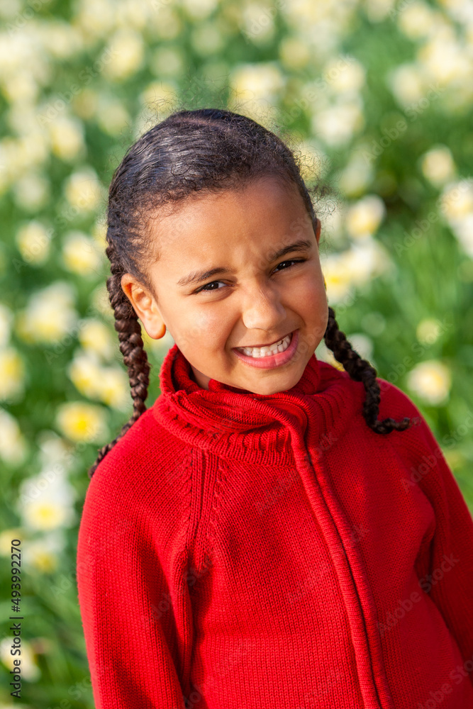 African American mixed race girl smiling standing in a field of daffodils African American mixed race girl smiling standing in a field of daffodils