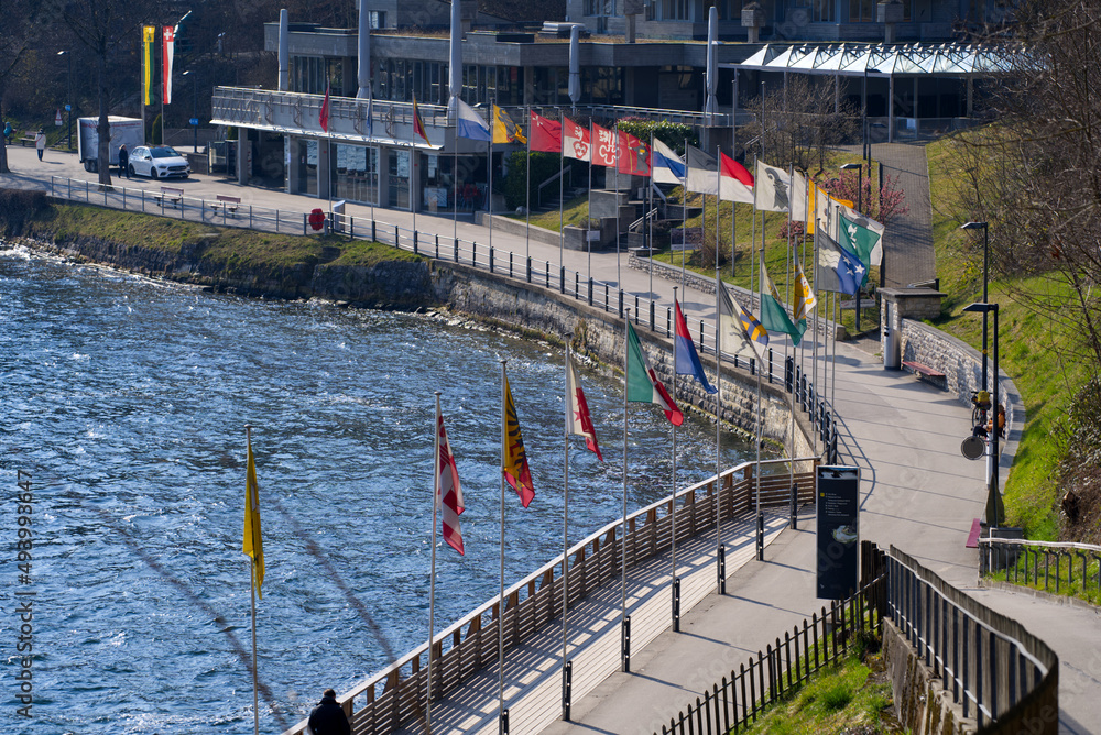 Naklejka premium Flags of all Swiss Cantons at border of natural pool of famous Rhine Falls on s sunny spring day. Photo taken March 7th, 2022, Zurich, Switzerland.