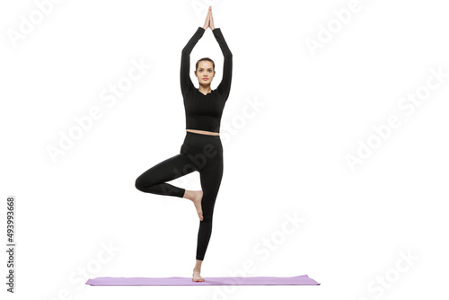 Portrait of young woman doing stretching and yoga exercises isolated over white studio background