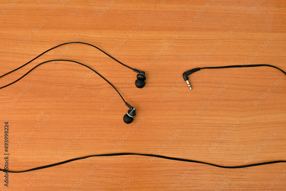 wired headphones tangled in a knot, on a wooden background wired headphones tangled in a knot, on a wooden background