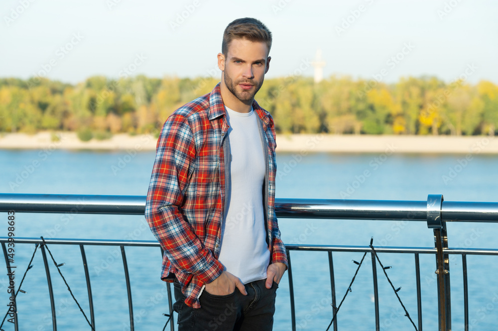 male fashion model. mens beauty. handsome man in casual checkered shirt. young unshaven guy outside