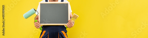 cropped man housepainter in work clothes hold paint roller brush and blackboard with copy space photo