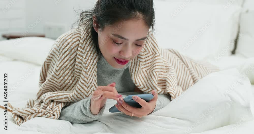 Beautiful young Chinese woman laying on bed , using mobile phone Beautiful young Chinese woman laying on bed , using mobile phone