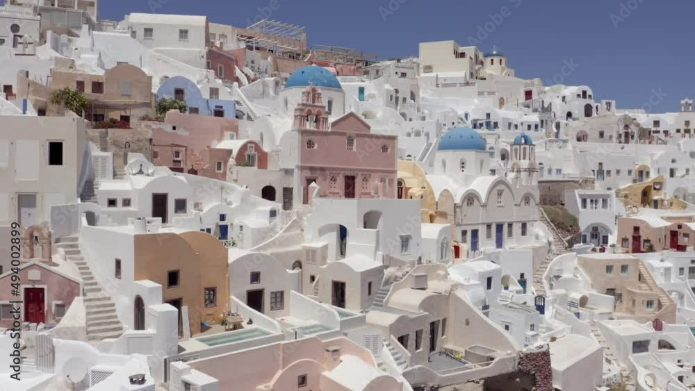 Aerial: pullback panoramic shot of Oia churches in Santorini, Greece on a sunny day Aerial: pullback panoramic shot of Oia churches in Santorini, Greece on a sunny day