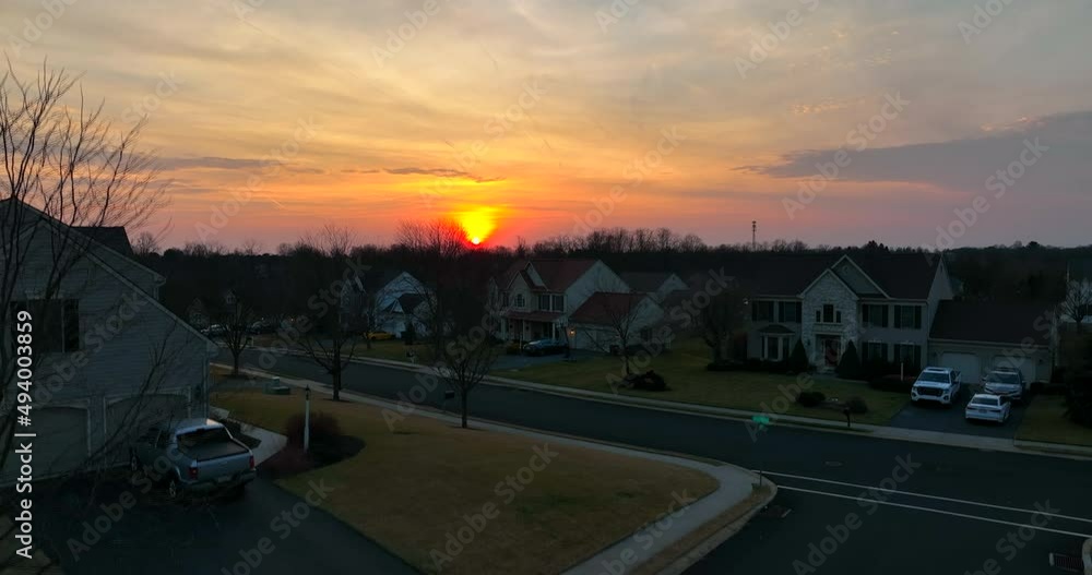 Suburban homes at night in winter sunset. Bare trees and American USA suburbia houses. Rising aerial to reveal colorful sunrise. Suburban homes at night in winter sunset. Bare trees and American USA suburbia houses. Rising aerial to reveal colorful sunrise.