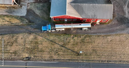 Milk truck tanker trailer for hauling milk from dairy farm. Aerial tilt up of American farm and red bar. photo