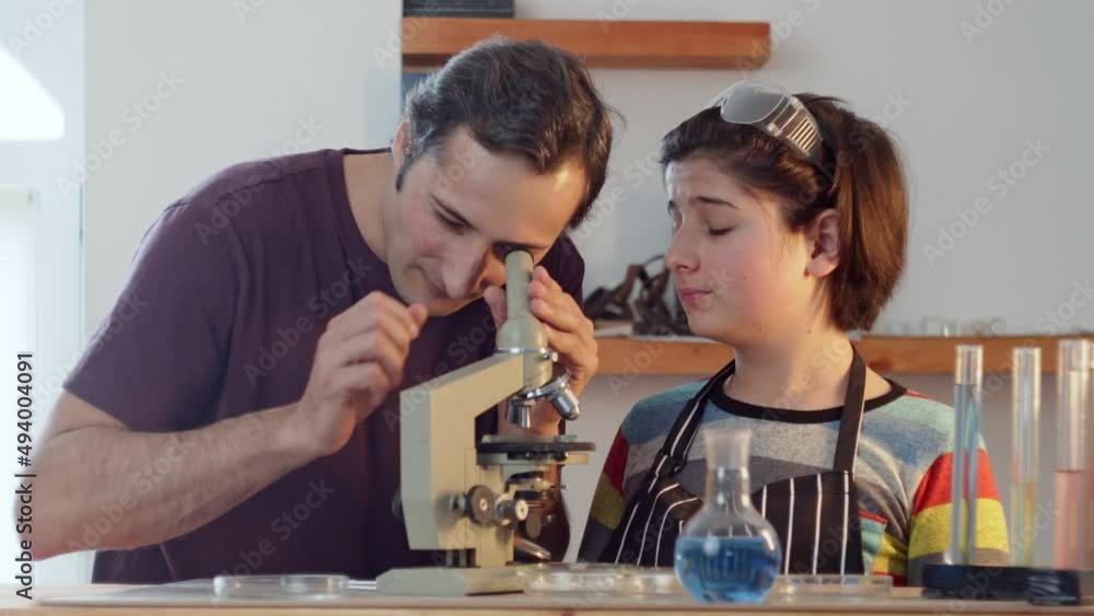 Father's Hidden Lab A father helps his son Teenager in a research home laboratory to ...