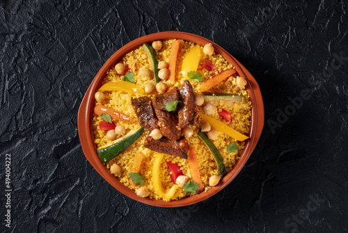 Meat and vegetable couscous, traditional Moroccan food, shot from the top, with chickpeas on a black background