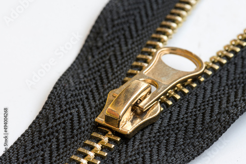 Black zipper with a gold runner lock on a white background.