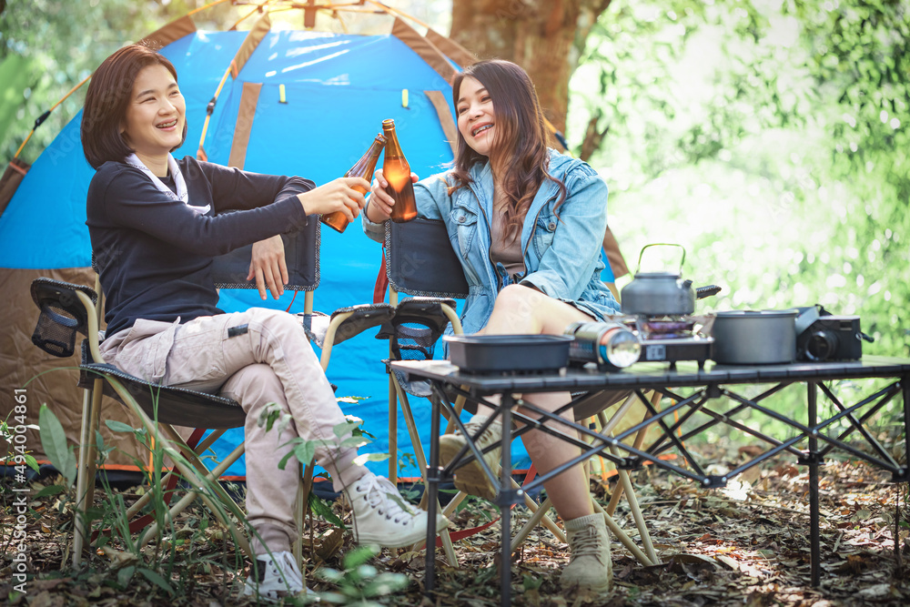 Happy two girls relaxing drinking wine camping summer holidays in forest. celebration and friendship concept Happy two girls relaxing drinking wine camping summer holidays in forest. celebration and friendship concept
