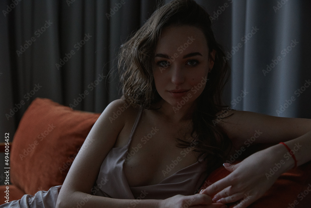 Obraz premium Attractive brunette woman posing in studio laying on sofa fashion style