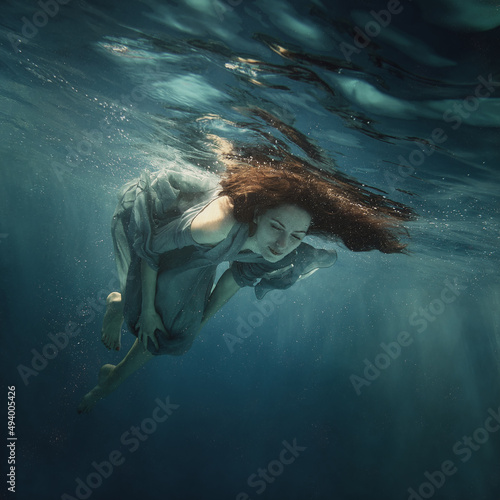 A woman in a dress swims under water as she flies in weightlessness © Dmitry
