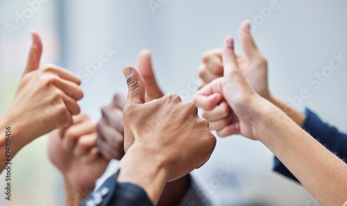 We absolutely love what youre doing. Shot of a group of coworkers with their arms raised in the thumbs up gesture.