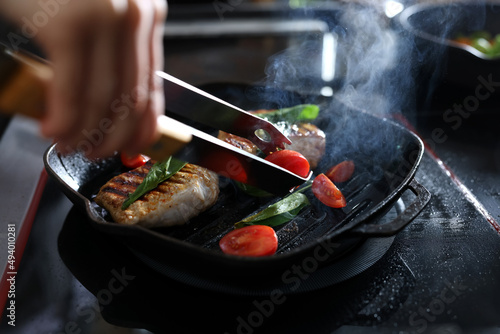 Professional chef cooking meat on stove in restaurant kitchen, closeup