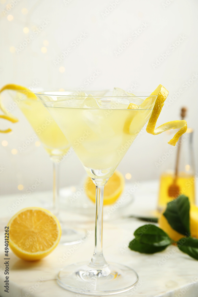 Delicious bee's knees cocktail with ice and lemon twist on white table