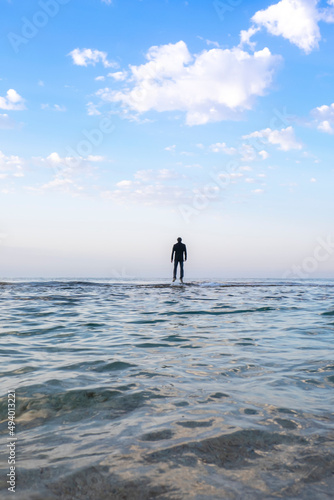 man wearing a long jacket walking on the water during a sunrise, Wet businessman walking to the water