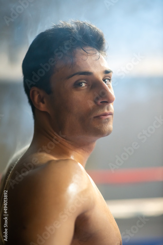 Portrait of serious shirtless boxer in ring. Handsome Portuguese man with muscular body at championship. Athlete concept