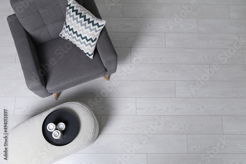 Stylish grey armchair and pouf with candles in room, top view. Interior design