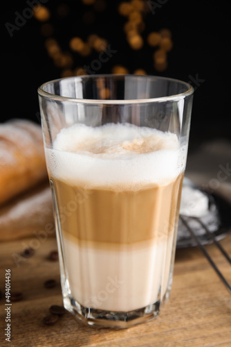 Delicious latte macchiato  croissant and coffee beans on wooden table  closeup