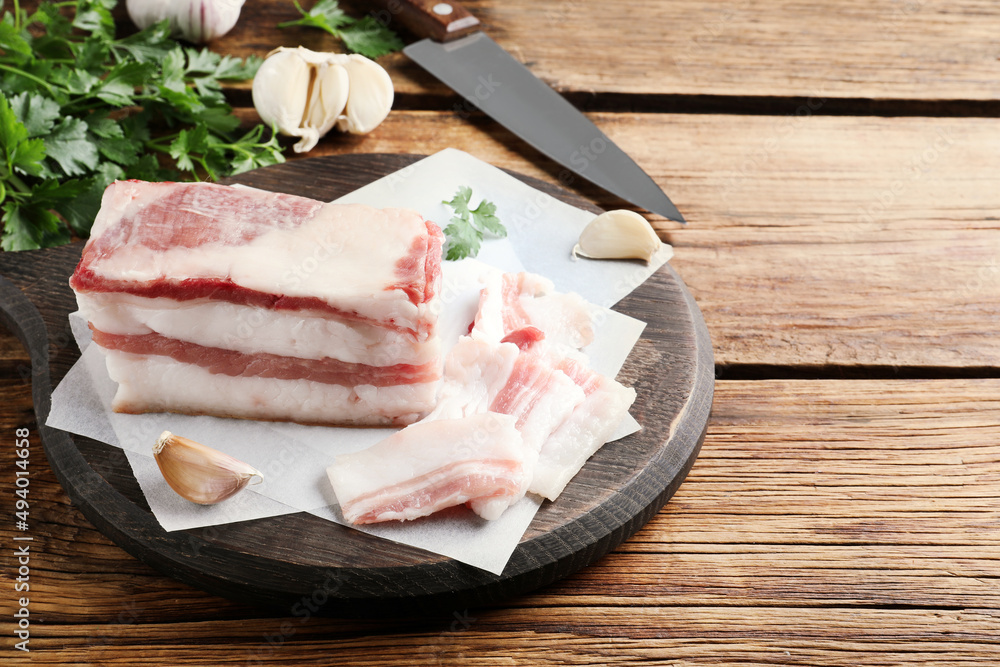 Tasty salt pork with garlic and parsley on wooden table, space for text Tasty salt pork with garlic and parsley on wooden table, space for text