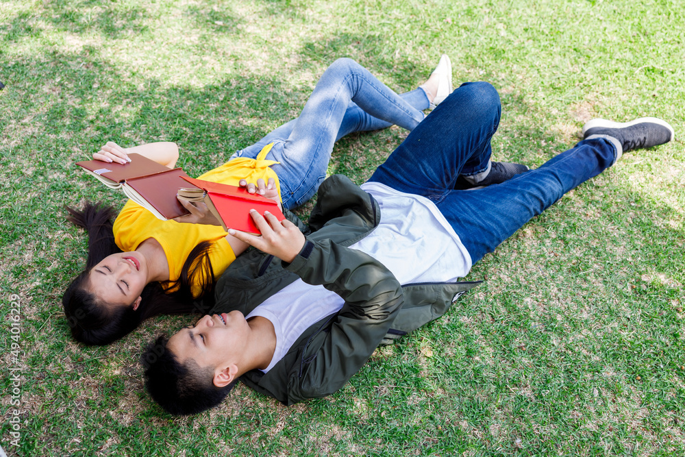 teenage student boy and girl lying on grren glass reading book in the park ,summer student concept,. teenage student boy and girl lying on grren glass reading book in the park ,summer student concept,.