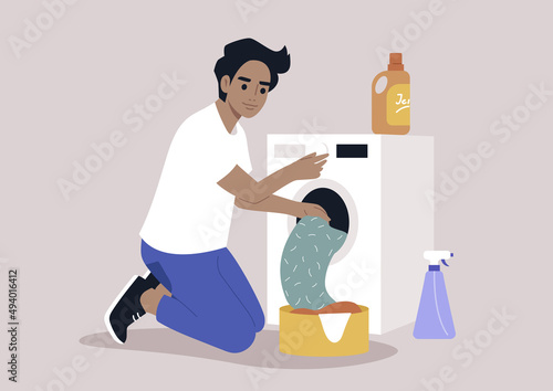 A young male Caucasian character loading a washing machine with a pile of laundry, domestic chores