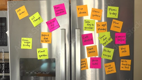 Refrigerator Door Filled With Reminder Notes and Hand Adds Taxes Due April 18th Memo Over File Taxes Memo