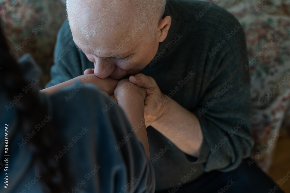 A hand of a granddaughter is holding a wrinkled hand of an old man symbolizing care, attention and unconditional love. A hand of a granddaughter is holding a wrinkled hand of an old man symbolizing care, attention and unconditional love.