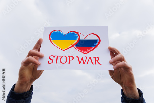 man hands holding of heart drawingon the cardboard with words Stop War. protesting against the Russian invasion. bannerdrawingon ukraine flag and russian flag cardboard. photo