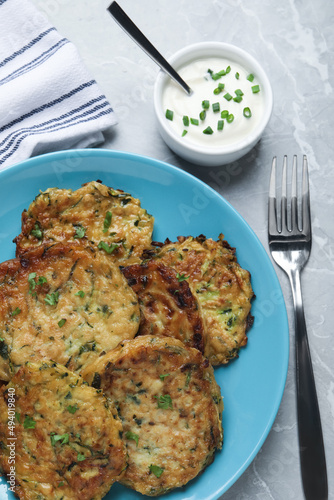 Delicious zucchini pancakes served on grey table, flat lay