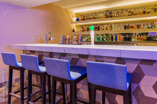 Modern bar counter with stools and different bottles of alcohol photo