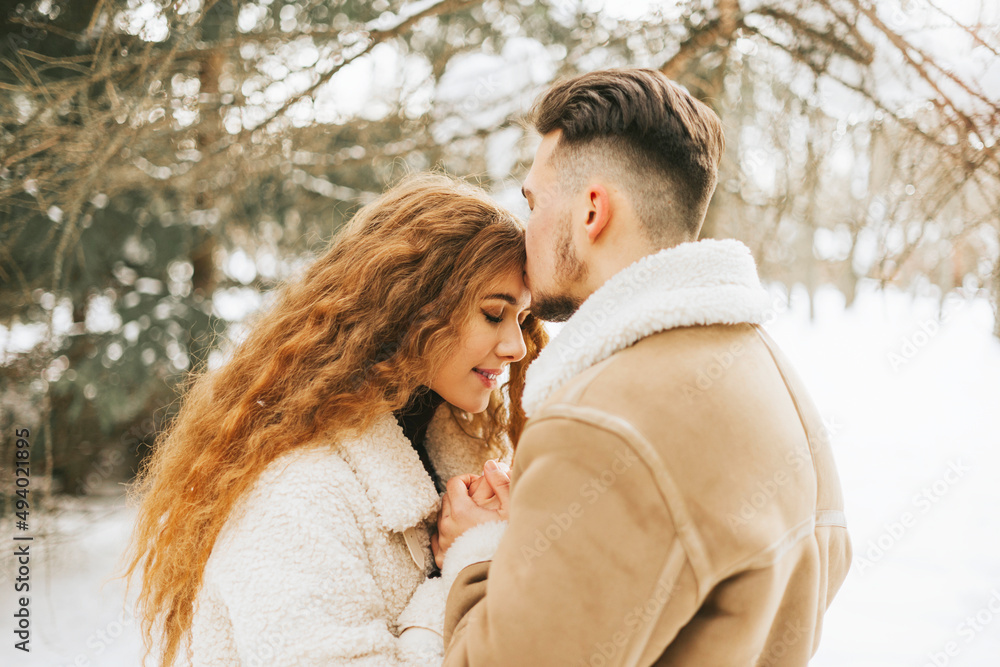 young couple in love man and woman in fashion stylish winter clothes standing in snowy pine forest and having fun spending time together, concept of valentine's day and newlyweds, tenderness and love young couple in love man and woman in fashion stylish winter clothes standing in snowy pine forest and having fun spending time together, concept of valentine's day and newlyweds, tenderness and love