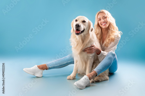 Young woman posing with her dog at blue studio