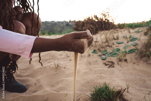 Crop black woman with handful of sand on seashore photo