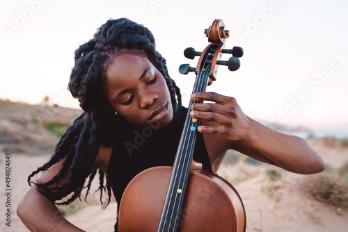 Black woman play cello on beach