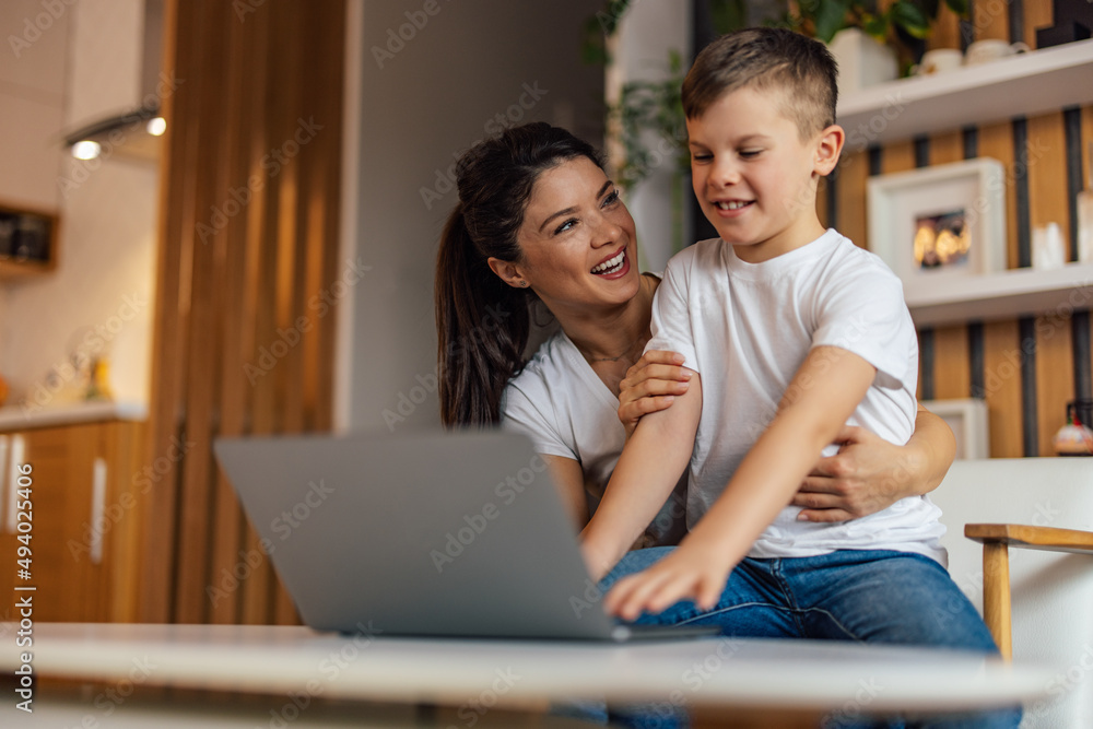 Young child, typing something, using a laptop, while sitting on the mom's lap. Young child, typing something, using a laptop, while sitting on the mom's lap.