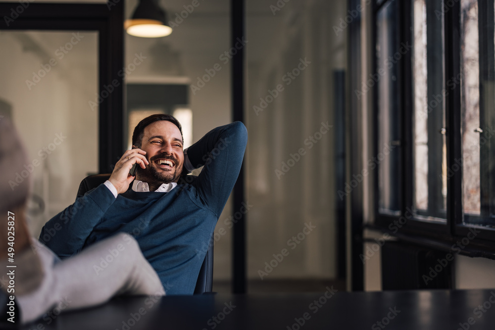 Fototapeta premium Happy businessman, enjoying his break at work, making a phone call, laughing.