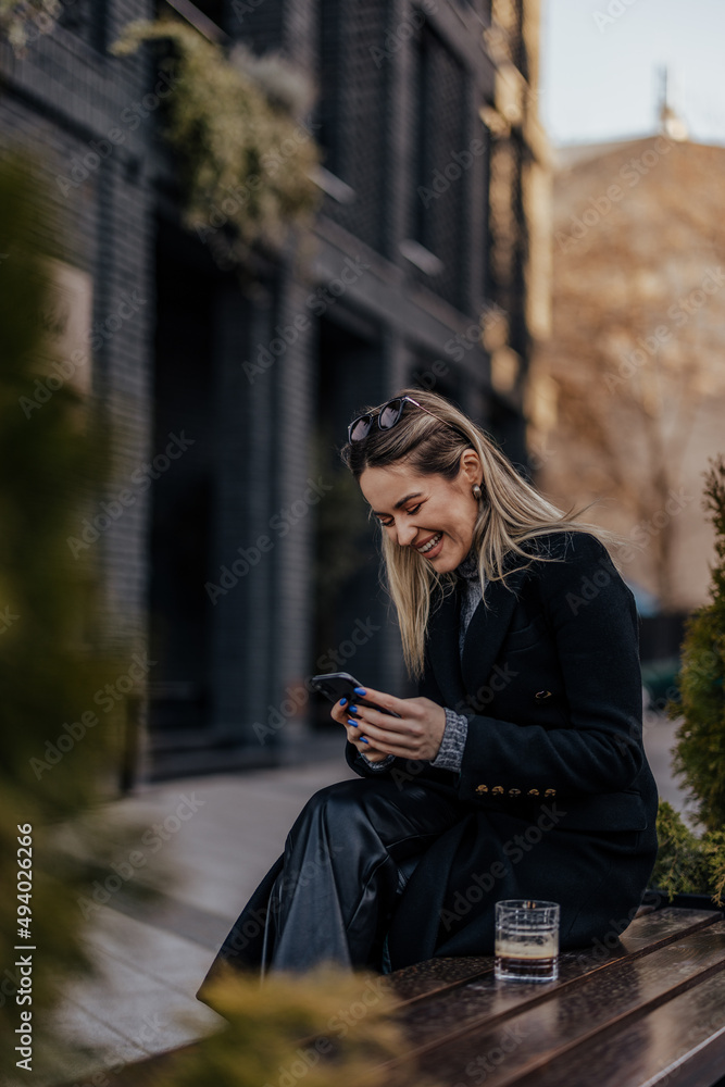 Delighted caucasian blonde woman, reading a funny joke on her phone.