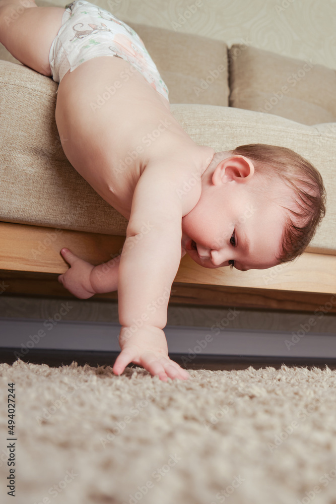 Infant baby falls off the sofa in the home living room. Toddler