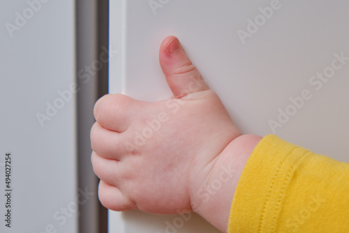 Danger for the baby to pinch the hand of the cabinet door or chest of drawers. Protect children from home furniture, kids safety photo