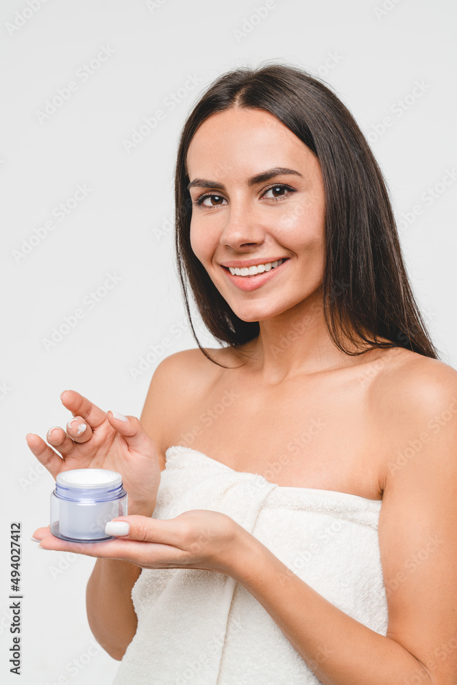 Vertical caucasian young woman applying moisturizer on her face, face skin care with soft mask cream creme, rejuvenation anti-acne anti-aging effect isolated in grey background. Beauty concept Vertical caucasian young woman applying moisturizer on her face, face skin care with soft mask cream creme, rejuvenation anti-acne anti-aging effect isolated in grey background. Beauty concept