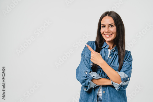 Happy smiling caucasian young woman with toothy white smile looking at camera pointing showing copy space free space isolated in white background