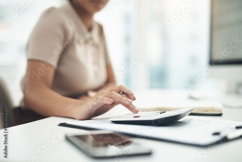 Working on her business earnings and expenses. Closeup shot of an unrecognisable businesswoman calculating finances in an office. © N Felix/peopleimages.com