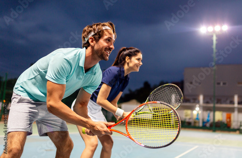 Fototapeta Naklejka Na Ścianę i Meble -  Tennis sport people concept. Mixed doubles player hitting tennis ball with partner standing near net