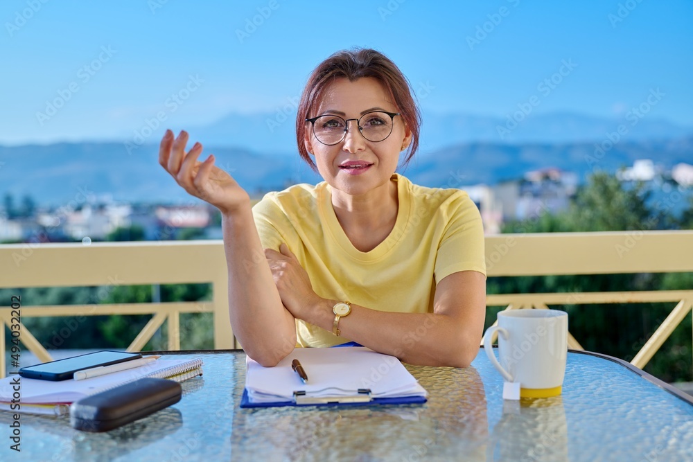 Portrait of business woman looking at webcam while sitting at home office desk