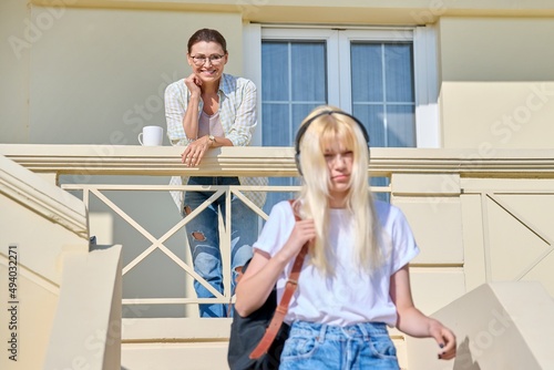 Middle-aged mother seeing off her teenage daughter on the porch of the house