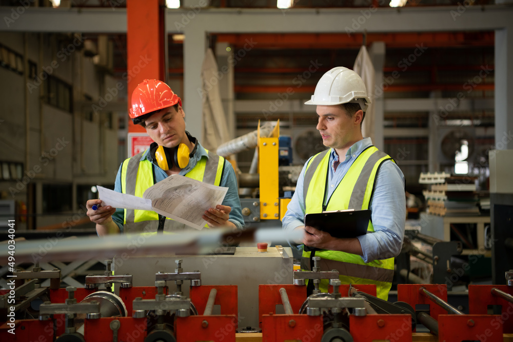 Two young engineers Testing and verifying the operation of the machines forming metal sheet tiles Two young engineers Testing and verifying the operation of the machines forming metal sheet tiles