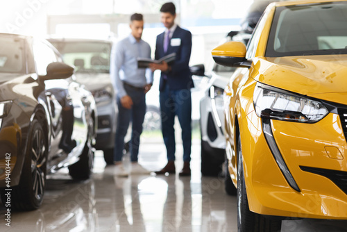 Customer standing among cars, having conversation with sales assistant photo
