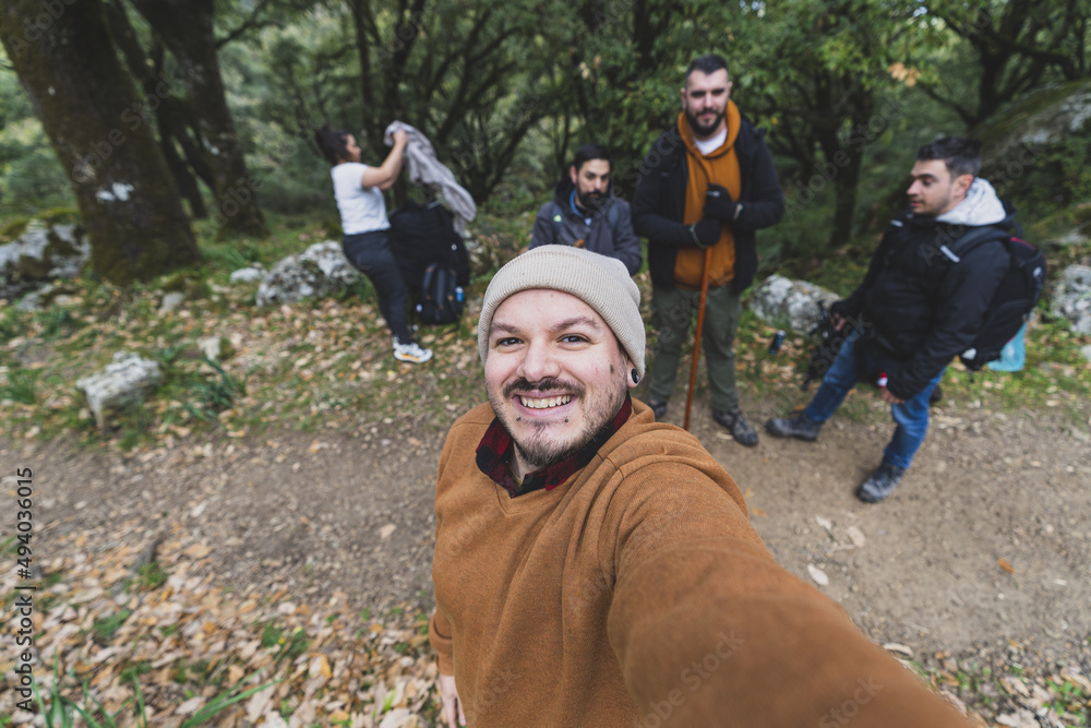 Young Caucasian man taking a selfie of a group of hikers while resting ...